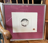 Framed print showing a black and white circular image of seated figures with maroon mat and silver frame.