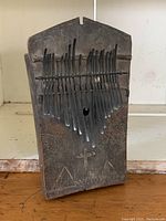 Front view of wooden thumb piano showing carved soundboard and metal tines