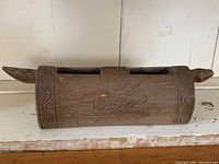 Carved wooden percussion instrument with crocodile image and side animal head extension
