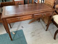 Full view of antique wooden desk showing rectangular shape, two drawers, and leather top.