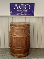 Full view of vintage oak apple barrel against a wainscoted wall with ACO Antiques sign.