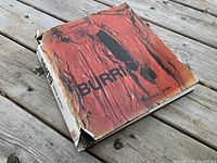 Front cover and spine of the hardcover book showing the dust jacket with red abstract art and 'BURRI' title, jacket is worn and torn.