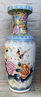 Front view of the tall vintage porcelain vase showing intricate famille rose floral paintings and peacock designs.