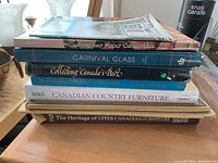 Stack of nine hardcover and folio books centered on antiques, collectibles and art prints.