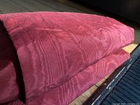 Close-up view showing folded wine-colored silk moire fabric with visible moire watermarked pattern and texture.
