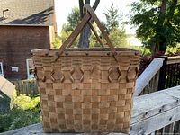 Front view of the rectangular woven basket showing the diamond knotting detail and riveted handles.