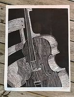Full view of black and white linocut print depicting a cello and chair on wooden deck background