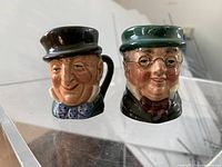 Front view of the two miniature toby jugs showing detailed facial features, colors, and glaze.