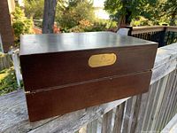 Exterior view of rectangular wooden box with dark finish and gold Remy Martin plaque on front.