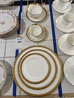 Overall arrangement showing four plates stacked by size with two teacups and saucers arranged separately.