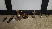 Overview photo showing all brass items including the brass pitcher, cups on a tray, lantern-shaped music box, and other small brass pieces arranged on carpet.