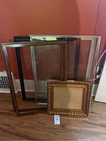 Five picture frames of varying sizes, placed leaning against a wall, showing overall shape and style.