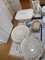 Porcelain serving dish with textured lid and pitcher with fruit motif on tile countertop