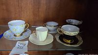 Shelf display of all five teacup and saucer sets side by side
