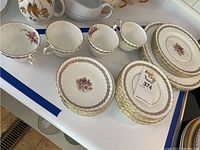 Overview of various cups and plates organized on a counter, showing floral and gold trim detail on each piece.