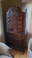 Full height photo of vintage wood cabinet showing multiple drawers and carved details on top panel.