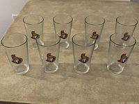 Lot of 8 clear 16-oz pint glasses with Ottawa Senators logo printed on the front, arranged in two rows on a beige surface.