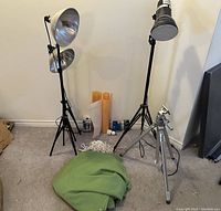 Photo showing the two large scoop lamps on tripods, smaller tripod with light, green screen blanket, rolls of diffusion filters, clips and cords.