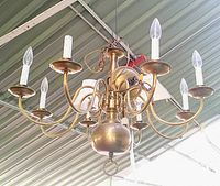 View of the antique solid brass chandelier from a side angle showing the 8 candle-shaped bulb holders with bulbs installed.