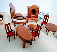 Photo showing piano, wooden hutch, oval and round tables, and red upholstered chairs