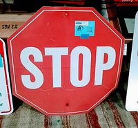 Front of the red and white octagonal STOP sign leaning against a surface. Visible scratches and wear.