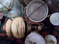 Photo showing multiple vintage canning Ball jars with metal and glass lids, and a woven basket bottle holder.