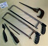 Lot overview showing vintage hand tools and saws arranged together on light background.