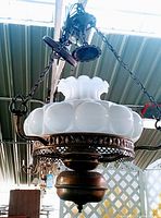 Full view of the vintage Victorian hanging lamp chandelier showing white glass shade, metal frame, and hanging chains.