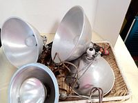 Overview of three large aluminum vintage adjustable Victor Smith studio lamps with bulbs and cords, showing lamp reflectors arranged in a basket