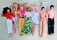 Seven vintage Barbie and Ken dolls with some clothing and a pink hair dryer accessory arranged on a green background.