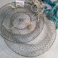 Top down view of two stacked vintage steel wire folding traps with attached miscellaneous blue and white ropes on the side.