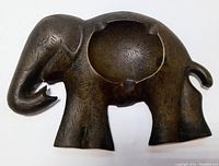 Side view of brass elephant shaped ashtray showing engraved texture and circular ash holder.