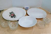Overview of all items in the lot showing the Johnson Bros floral bowl, two bone white platters, and six clear cut glass bowls
