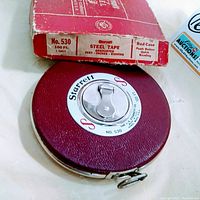Photo showing the vintage Starrett steel tape measure model No. 530 with its red textured case, central push button, and original labeled box with clear markings of model, size, and manufacturer details.