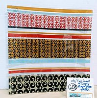 Top view of colorful rectangular glass platter plate featuring horizontal bands of swirl designs in red, black, and yellow-orange with blue and white stripes.