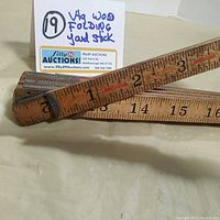 Close-up of the wooden folding yard stick highlighting the black and red measurement markings, blue tips, and metal hinges.