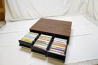 Wooden 3-drawer cassette case with all drawers fully open showing neatly stored audio cassette tapes