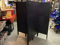 Black metal 4-way pegboard display unit fully standing in retail or workshop environment