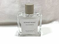 Front view of clear rectangular glass bottle with white label showing product name and size.