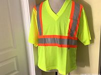 Front view of a high-visibility yellow mesh T-shirt with reflective strips and a front chest pocket on a mannequin.