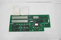 Full view of the green PC board with visible electronic components and two ribbon cable connectors.