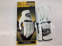 Packaged Callaway golf glove in retail box next to the glove in plastic sleeve, front view showing brand and product line.