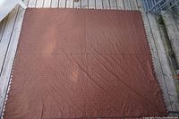 Brown quilt cover blanket laid flat, showing surface texture and stitched patterns.