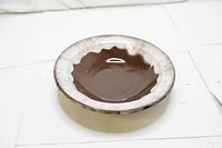 Front view showing the brown center glaze with a white irregular rim on the vintage pottery serving plate.