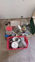 Photo showing multiple plastic storage containers including a red tub and clear jars filled with assorted screws, nuts, bolts, washers and small hardware pieces.