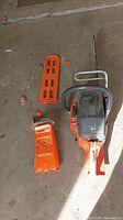 Chainsaw body, guide bar, plastic scabbard, File-N-Guide box, spring and hook laid out