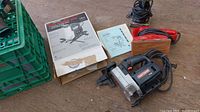 Craftsman jig saw, two sanders, boxes, and manuals laid on floor