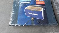 Blue Mastercraft branded folder with elastic clasp holding the sandpaper sheets, unopened and sealed in plastic wrap.