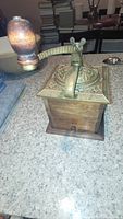 Full view of the vintage coffee grinder showing wooden base and cast iron top with handle and knob