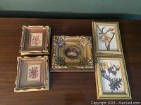 Overview of all five framed floral artworks on a wooden surface.